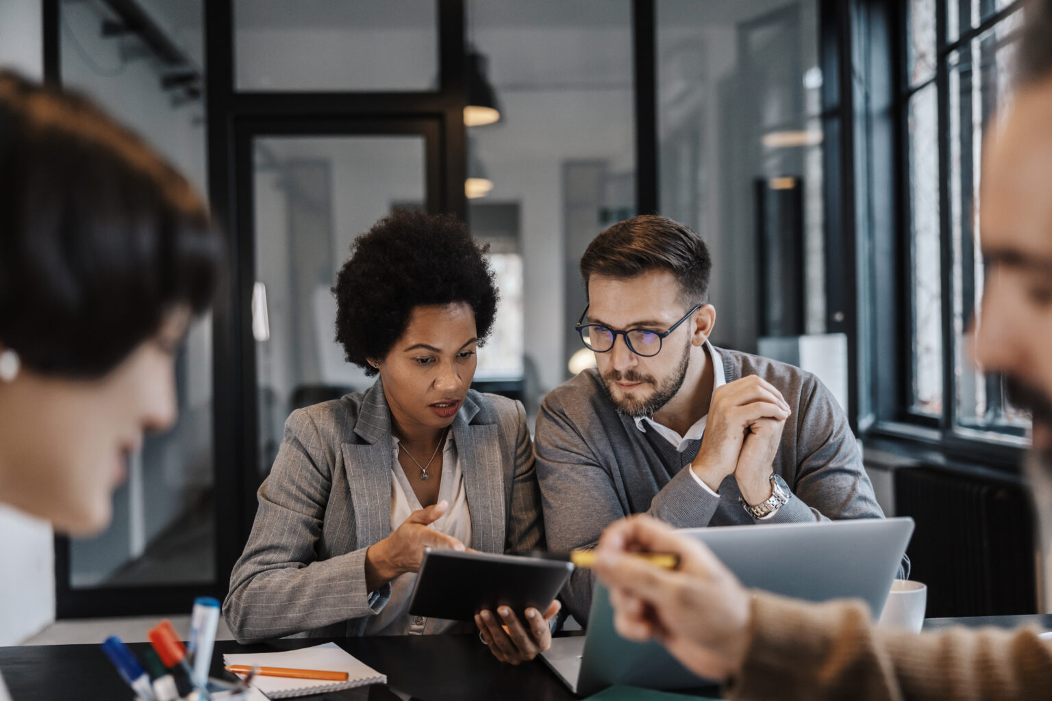 A multicultural group of experts is sitting at the office and solving problems on gadgets.